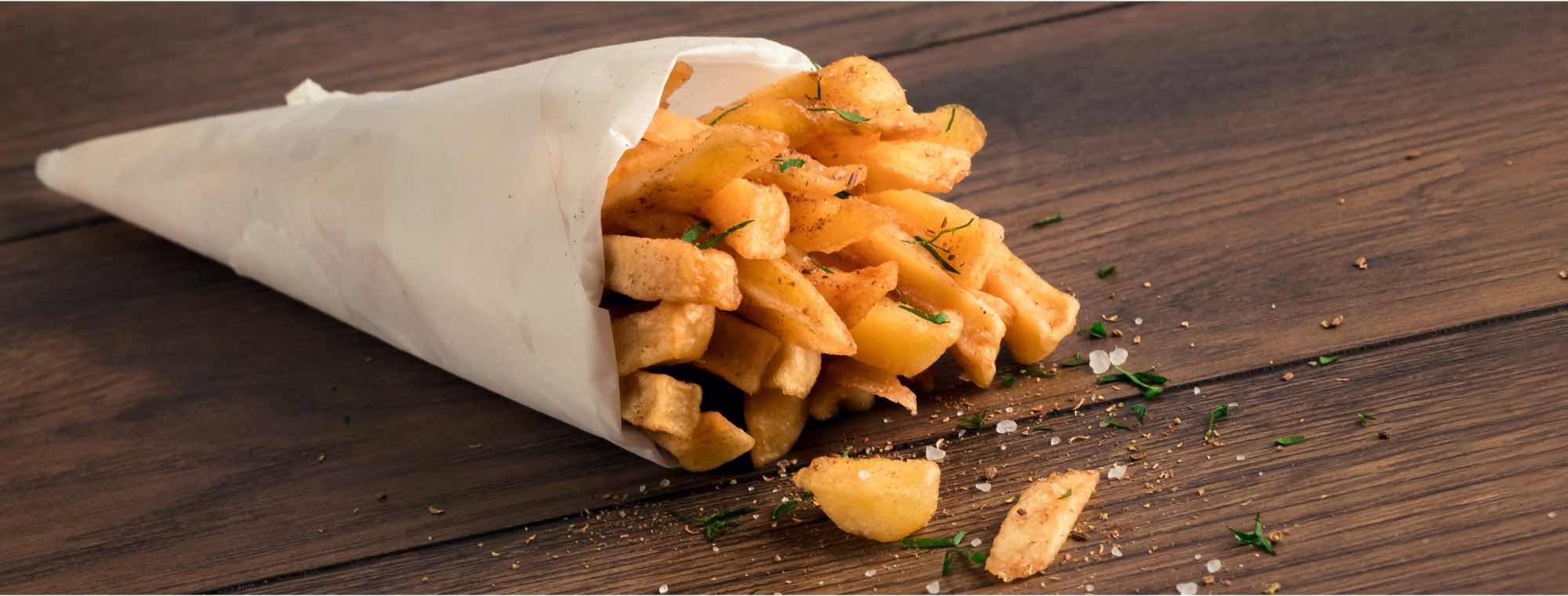 Fresh hot chips are packaged in an open paper bag
